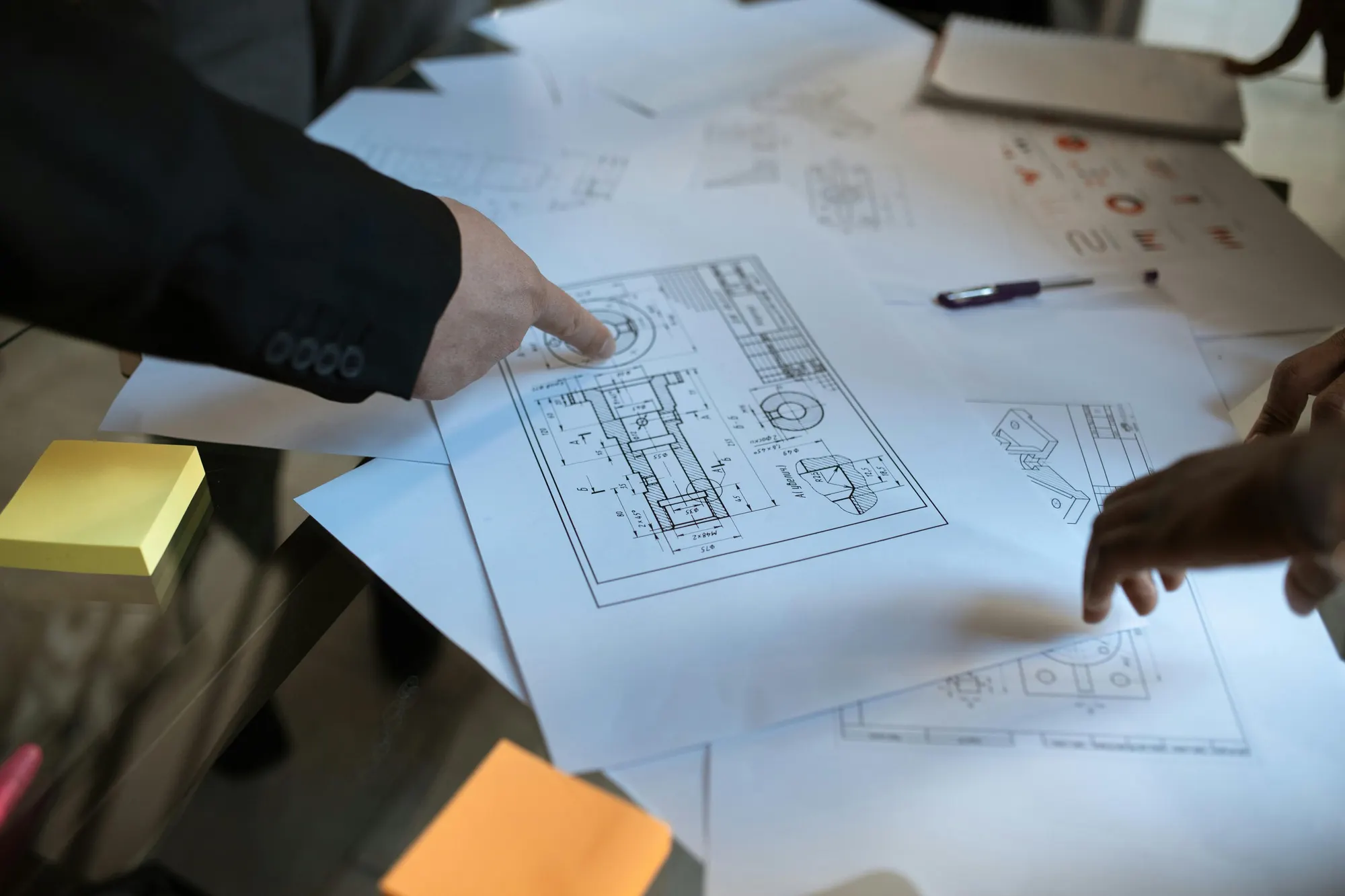 Hands reviewing civil engineering plans on a table